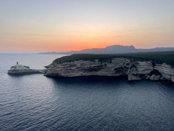 Stunning sunset over rocky cliffs by tranquil waters. Serene evening sky casting vibrant colors over a peaceful coastal landscape.