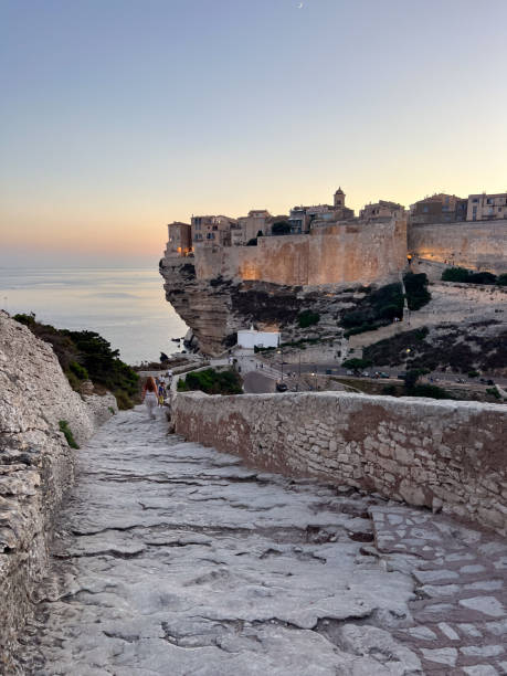 Historic town of Bonifacio perched on limestone cliffs at sunset. Serene coastal landscape with ancient architecture. Perfect travel destination on Corsican coast.