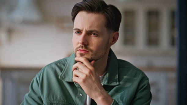 Pensive man thinking work at spacious apartment closeup. Frowning guy texting