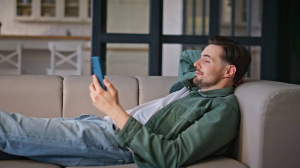 istock Relaxed man watching greenscreen smartphone lying comfortable home couch closeup 2199687071