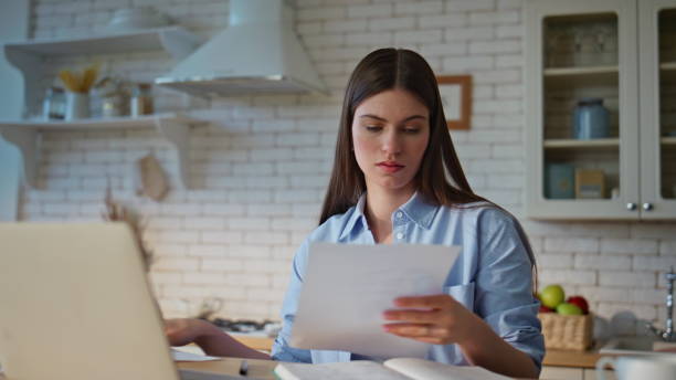 istock Woman accountant reviewing documents managing paperwork with laptop closeup 2199687130