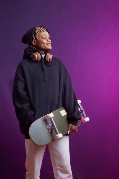 istock Young lady with headphones and skate standing 2199687374