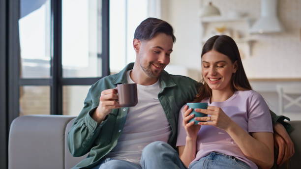 istock Romantic couple communicating home sitting cozy couch with coffee cup closeup 2199693580