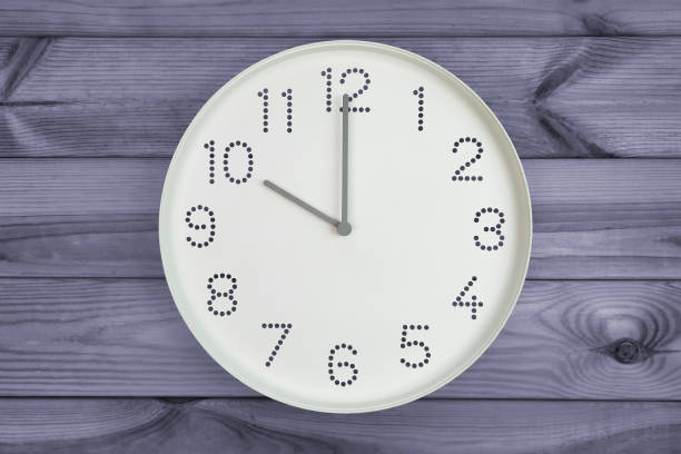 istock Round white wall clock with black dotted hour markers at 10 o'clock on grey wood background. concept of daily regime, daily morning routine, Business time reminder, office clock on wooden 2199696005
