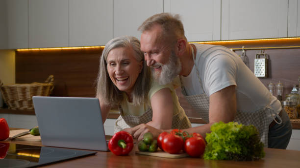 istock Older Caucasian couple middle-aged spouses family using laptop device at home kitchen choosing food delivery fresh vegetables online shopping natural products order retired woman and man laughing fun 2199698945