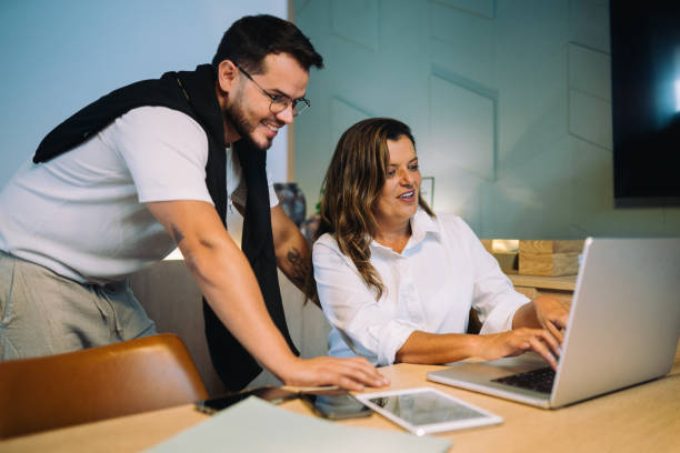 istock Coworkers smiling and working on a project on a laptop at the office 2199699531