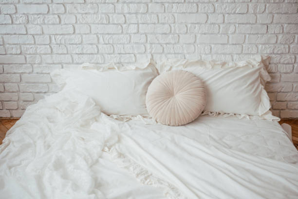 istock Soft white bedding on a minimalist bed with a decorative pillow 2199700033