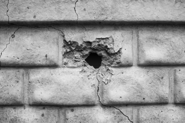 istock Cracked wall with a hole revealing darkness in a desolate setting. Damage after missile attack 2199700137