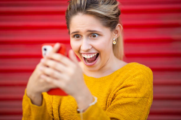 istock Excited young woman looking at mobile phone 2199700268