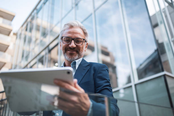 istock Confident businessman using digital tablet outside modern office building 2199700741
