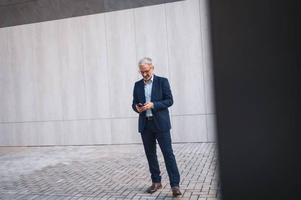istock Professional businessman using smartphone outside modern office building 2199700759