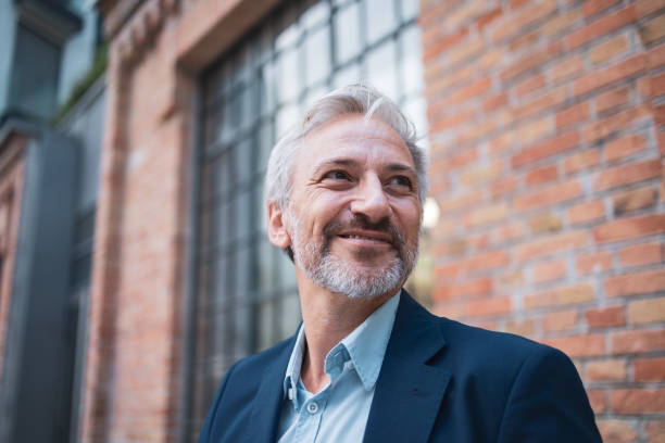 istock Confident mature man smiling outdoors in urban setting with brick wall 2199700768