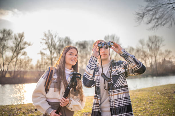 istock Happy couple is watching nature with binoculars while is hiking in mountain. 2199704381