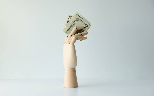 A hand holding a stack of fifty dollar bills