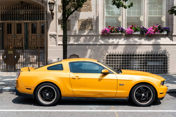 New York City, USA - August 05, 2023: 2011 Ford Mustang V6 yellow car passenger side view, parked.