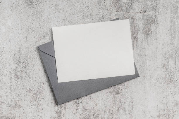 Gray envelope with blank card on concrete background. Invitation, greeting card mockup.