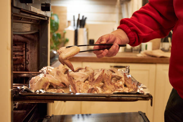 istock man cooks chicken wings in the oven 2199764914