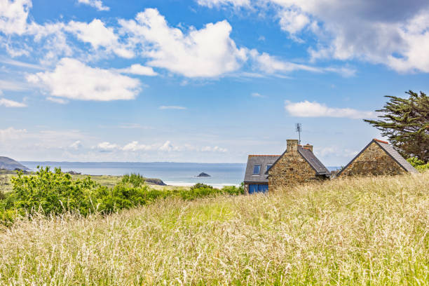 Seascape view from a grass meadow with old stone cottage at the coast