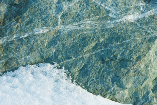 Fresh white winter snow on natural green rock abstract textured background
