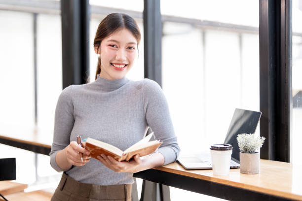 istock Creative young woman holding notebook standing in her studio, looking to carmera 2199775143