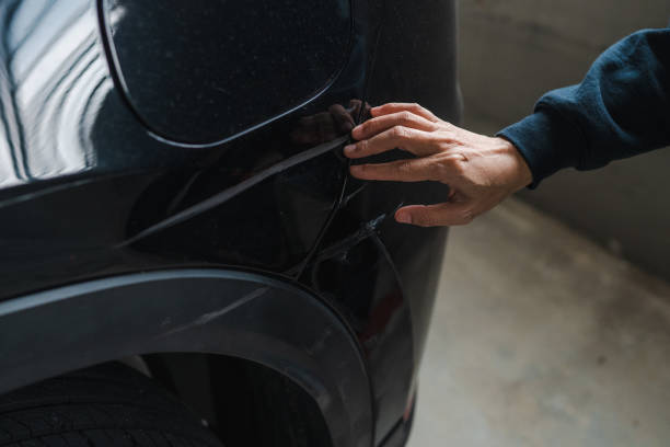istock Woman hand pointing at dent on black car close up view 2199777096