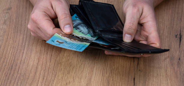 istock Male hand taking new 50 100 Australian banknotes in black leather wallet. 2199778425