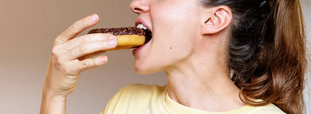 istock Woman eating chocolate donut side view photo 2199780642