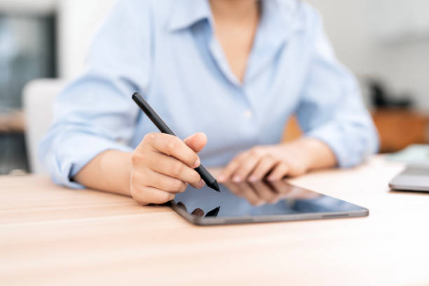 istock Woman hand using stylus pen writing on tablet screen. 2199782856