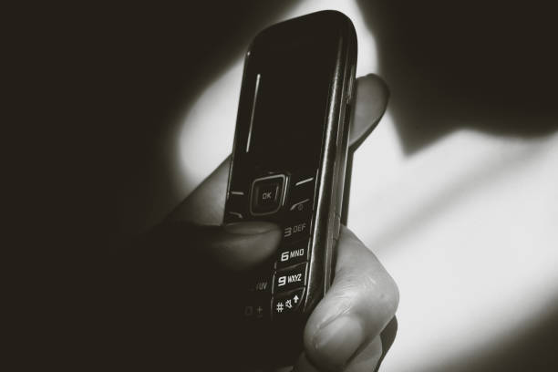 istock Hand holding a classic or vintage cell phone in low light 2199783106