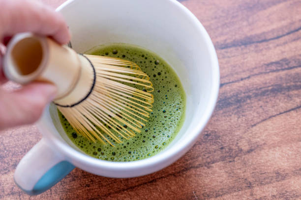 istock Hand whisking matcha tea in a white ceramic cup with a bamboo whisk 2199783634