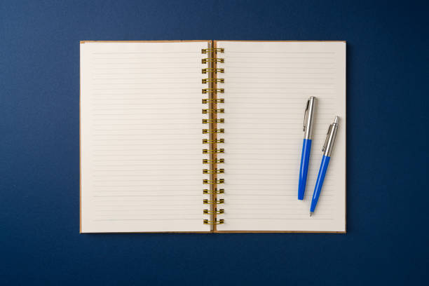 istock Top view of notebook and ballpoint pen on blue background 2199785244