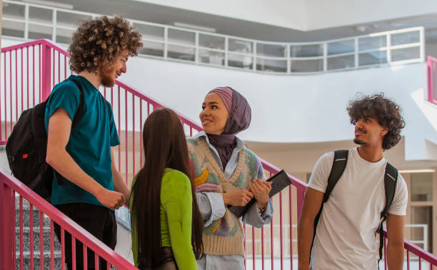 istock A group of happy diverse college students hanging out they are talking with each other while walking in the university hallway. 2199785336
