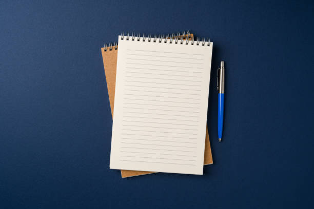 istock Top view of notebook and ballpoint pen on blue background 2199785358