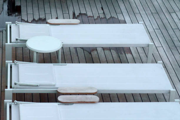 istock White sun loungers on wet wooden deck after rain 2199785621