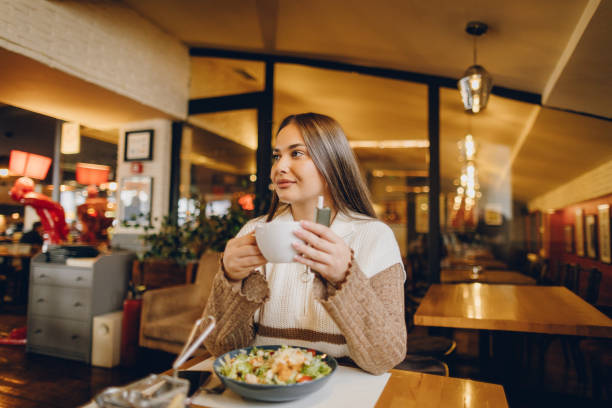 istock Beautiful young woman drinking coffee before breakfast in coffee shop 2199792743