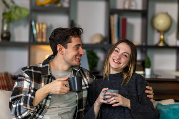 istock Happy young couple is relaxing on a sofa, drinking coffee and enjoying a pleasant conversation in their cozy living room 2199798849