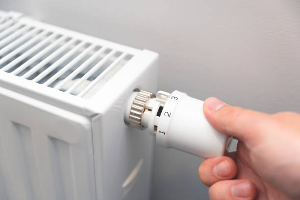 istock Modern white radiator, hand holding thermostat 2199803807
