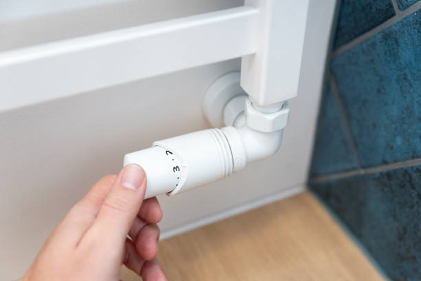 istock Modern white radiator, hand holding thermostat 2199803825