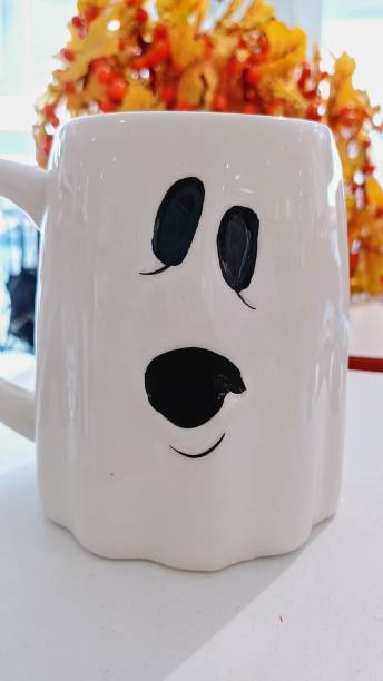 istock White color coffee mug. Halloween, white mug with spooky ghost eyes 2199811350