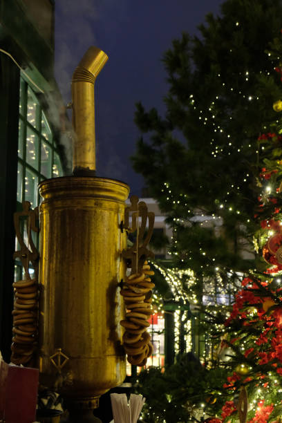 Festive decorations, including apples and grapes, hang from a wooden stall. In the background, the illuminated Christmas tree and TV tower create a magical holiday scene against the night sky