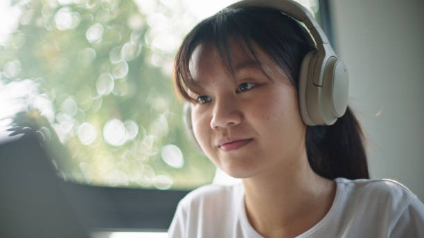 istock Teenager using laptop while wearing headphones. 2199815070