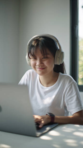 Teenager using laptop while wearing headphones.