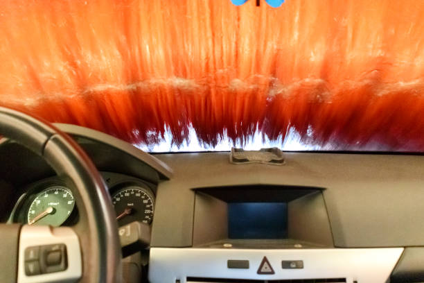 interior of a car showing a partial steering wheel and front panel as the car passes through a car wash