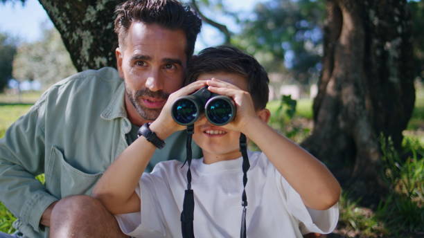 istock Father son enjoying birdwatching on sunny day closeup. Kid staring binoculars 2199817262