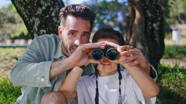 istock Little boy looking binoculars forest having outdoor adventure with daddy closeup 2199817598