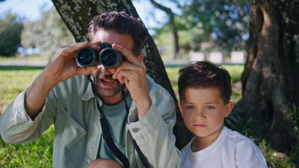istock Closeup family enjoying birdwatching looking binoculars nature. Boy man bonding 2199817687