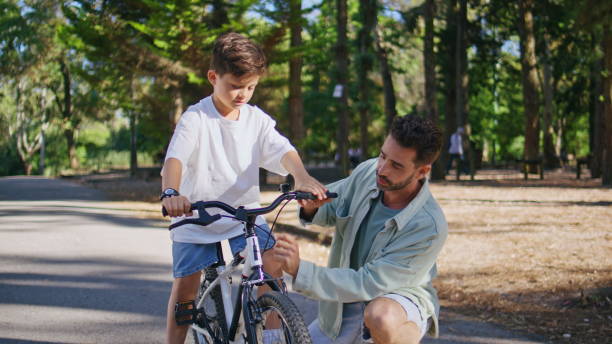 istock Daddy explaining child cycling in autumn park closeup. Kid learning ride bike 2199818415