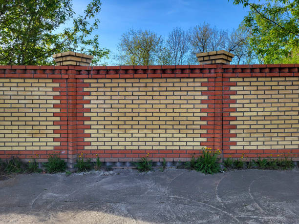 A yellow and red brick fence against a blue sky background