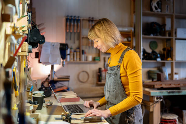 istock Successful female carpenter fulfill client requests on laptop. Coordinate materials, manage finances 2199824103