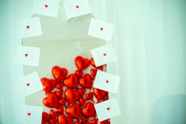 A tall mirror in the room is decorated with letters with hearts. Each envelope has a small heart. The mirror reflects large red heart-shaped balloons.